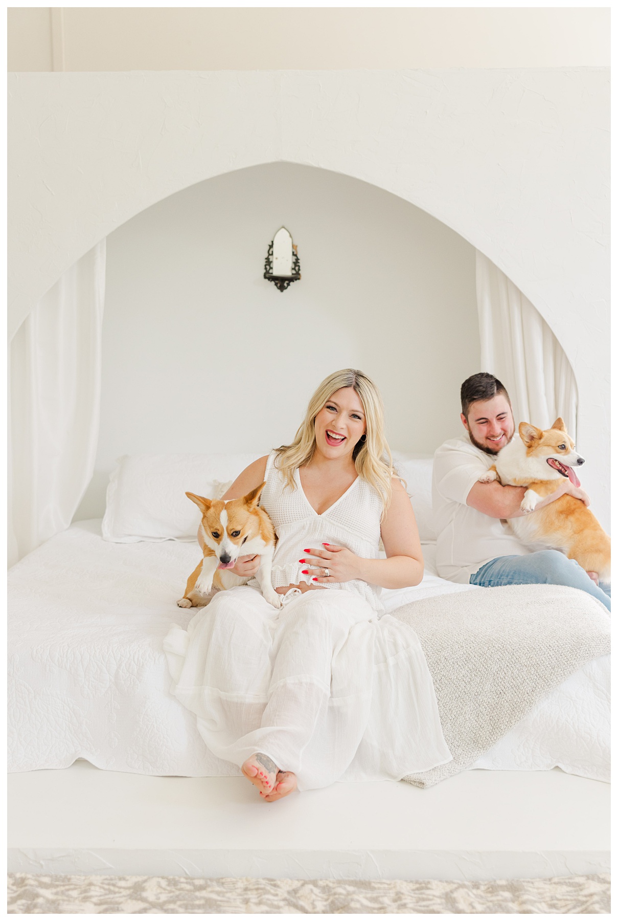 Hannah and Andrew sit on the bed with their dogs for their studio maternity photo shoot at The Rich Hippies House