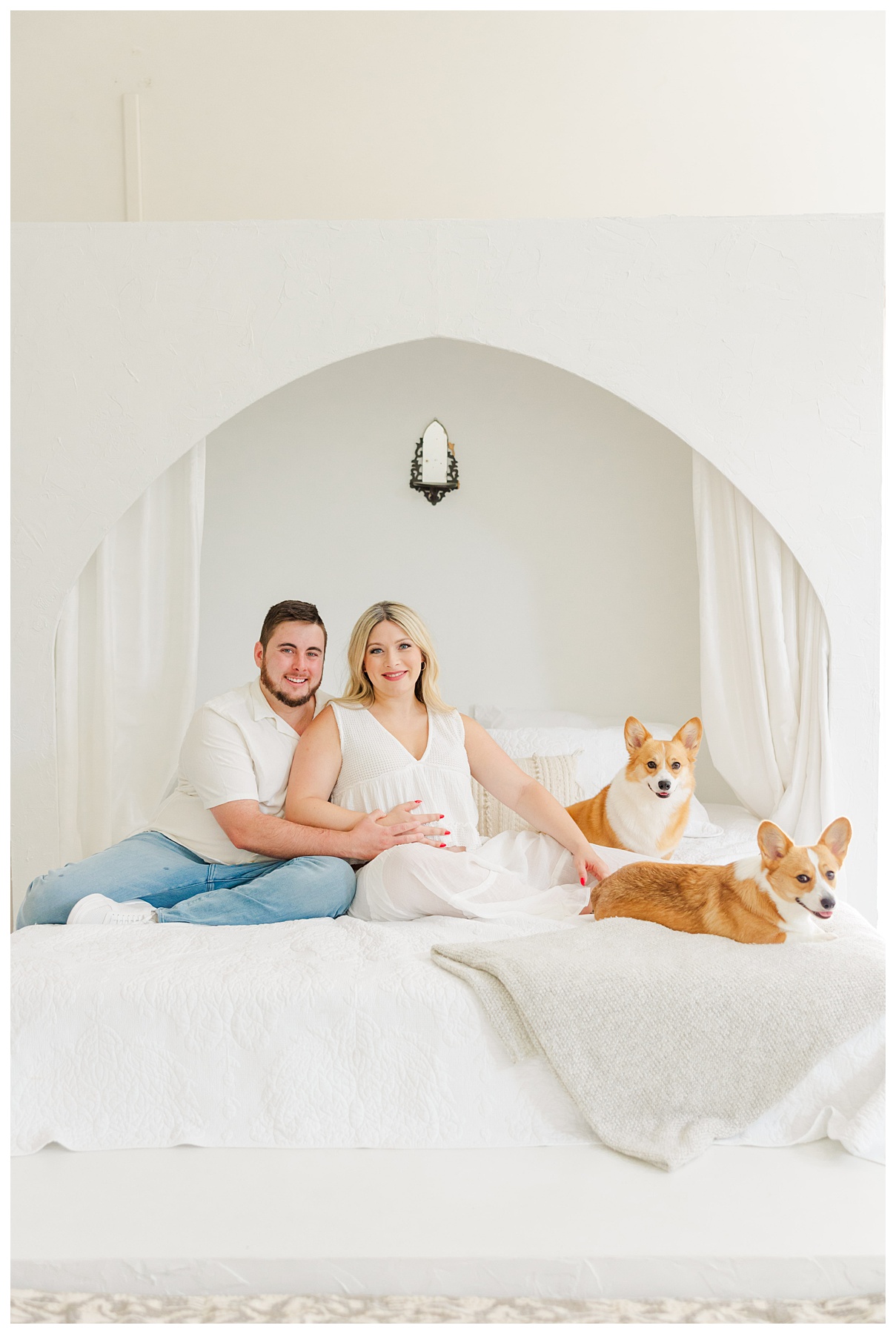 Hannah and Andrew sit on the bed with their dogs for their studio maternity photo shoot at The Rich Hippies House