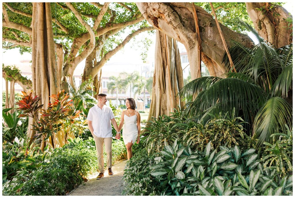 A couple walks through the garden for their engagement photos at The Boca Raton resort 