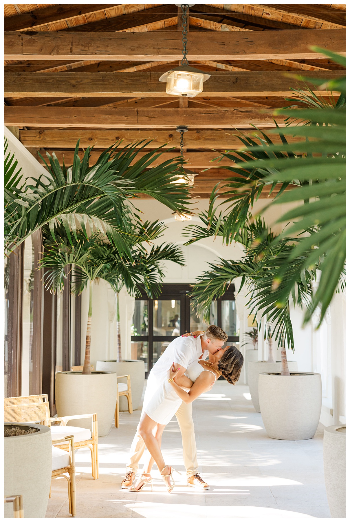 A couple kisses and dips in the hallway for their engagement photos at The Boca Raton resort 