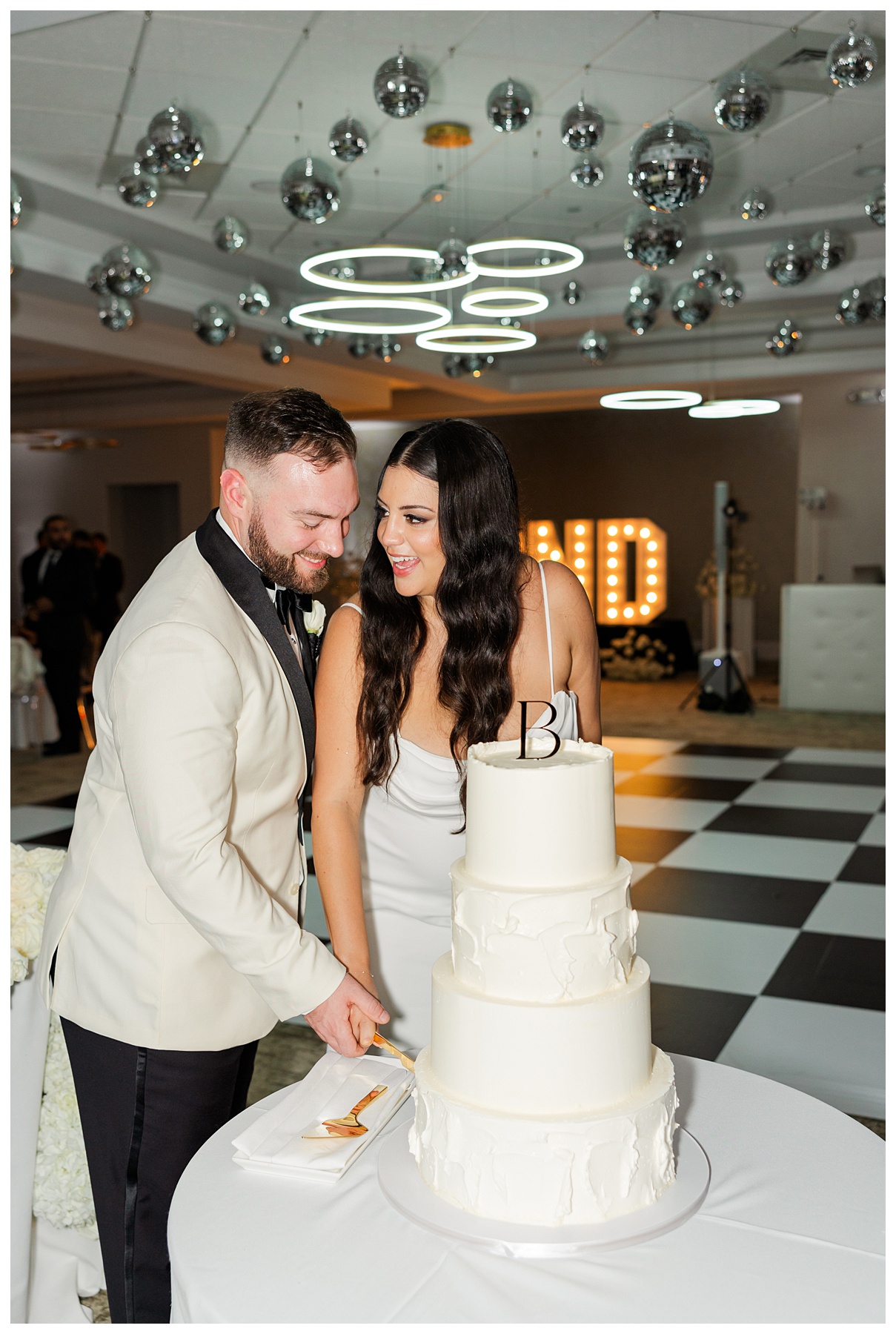 Erica and Stephen cut their wedding cake on the checkered dance floor at The Parkland Golf and Country Club