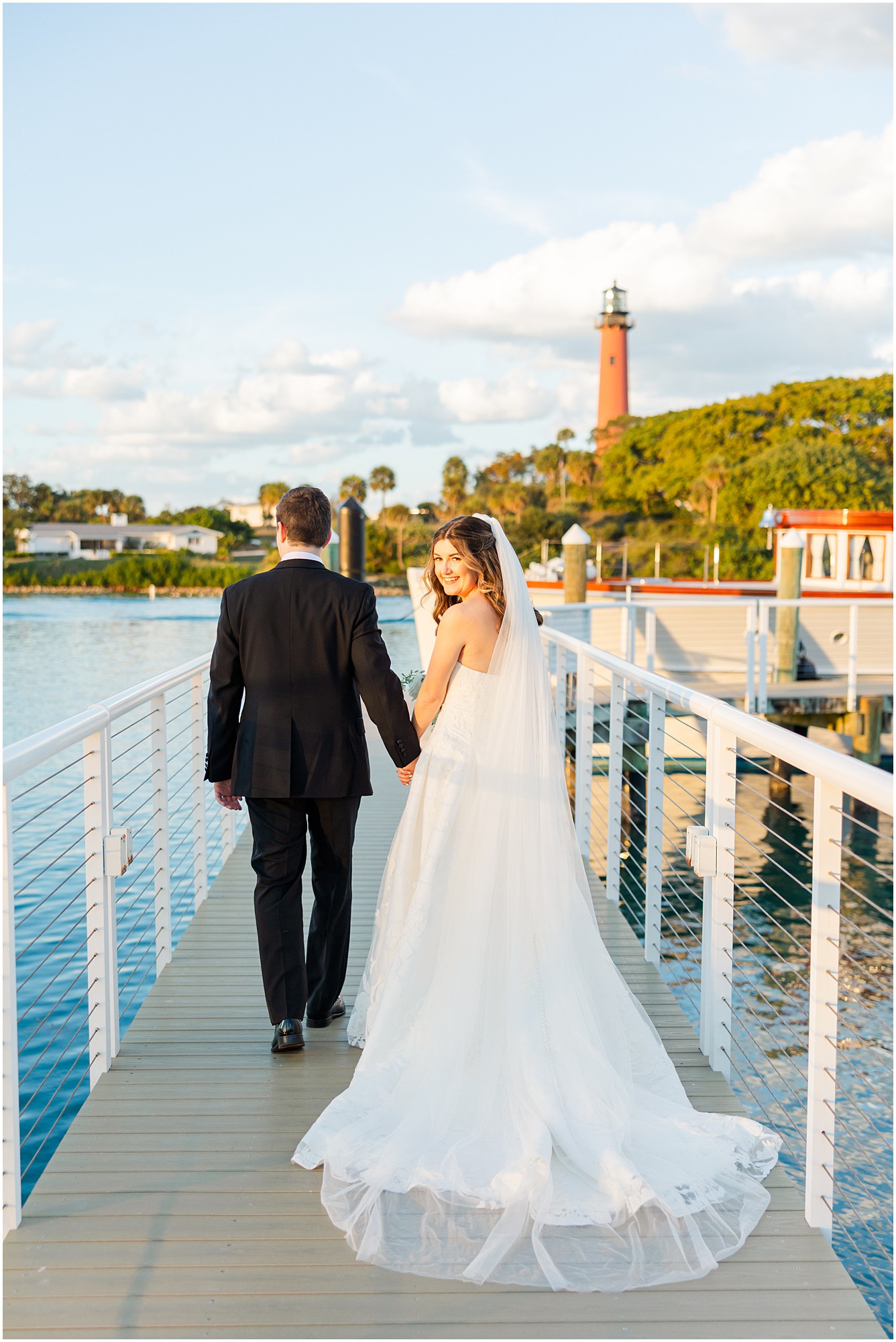 bride and groom walking on the dock at their Pelican Club wedding reception